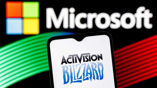 A phone showing the Activision Blizzard is held up in front of Microsoft's squares logo.