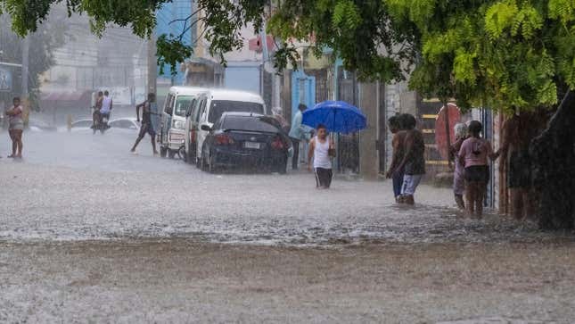 People walk through a street flooded by the rains of Tropical Storm Franklin in Santo Domingo, Dominican Republic, on August 22, 2023. 