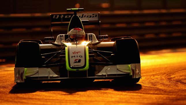 A photo of the white and green Brawn GP car racing at sunset. 