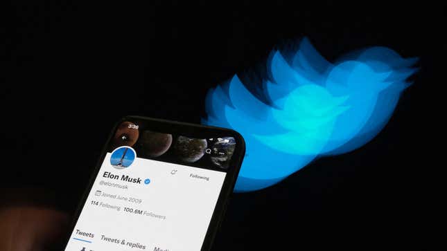 A phone with Elon Musk's Twitter profile is shown against a black background along with a blurred Twitter logo.