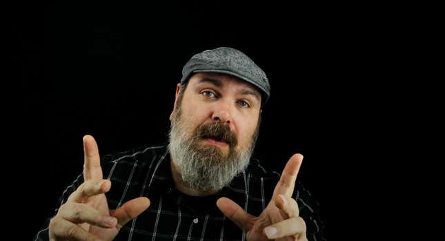 Mike Fahey of Kotaku points two fingers upward in a pitch-black room.