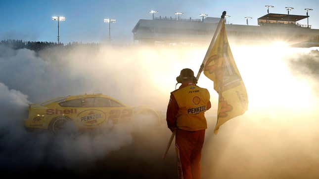  A crew member of the No. 22 Shell Pennzoil Ford waves the 2022 NASCAR Cup Series Championship flag as driver Joey Logano celebrates with a burnout after winning the 2022 NASCAR Cup Series Championship at Phoenix Raceway on November 06, 2022 in Avondale, Arizona. 