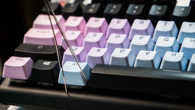 A photo showing the keycap puller wires cradled around the corners of an individual keycap on a mechanical keyboard