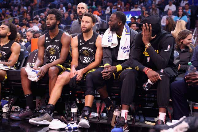 PHOENIX, ARIZONA - NOVEMBER 16: (L-R) Andrew Wiggins #22, Stephen Curry #30, Draymond Green #23 and Jonathan Kuminga #00 of the Golden State Warriors sit on the bench during the second half of the NBA game at Footprint Center on November 16, 2022 in Phoenix, Arizona. The Suns defeated the Warriors 130-119.