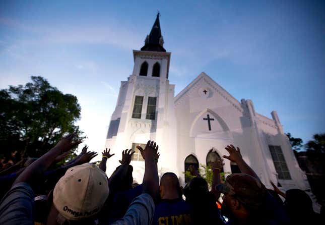 The men of Omega Psi Phi Fraternity Inc. lead a crowd of people in prayer outside the Emanuel AME Church, after a memorial service for the nine people killed by Dylann Roof in Charleston, S.C.