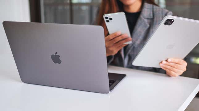 person using a macbook, iphone and ipad simultaneously 