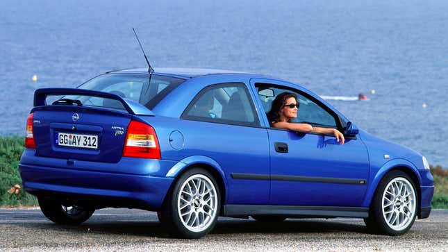 A photo of a blue Opel Astra car with the window down and a person leaning out. 