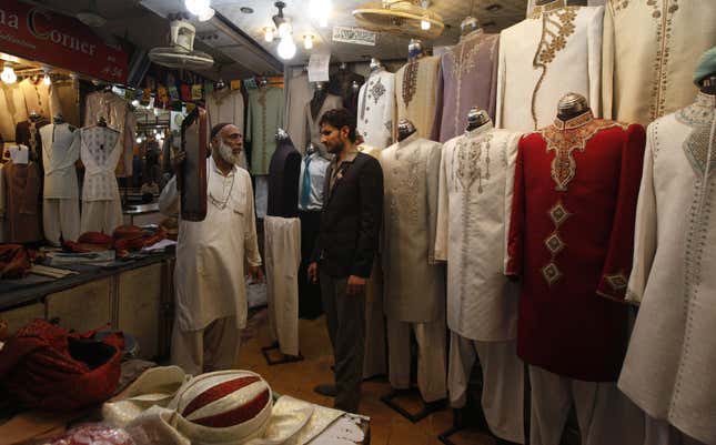 A shopkeeper in Karachi, Pakistan, helps a customer pick out a traditional dress ahead of Eid.