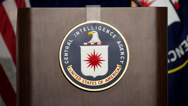 A lectern with the CIA logo on it flanked by a U.S. flag and CIA flag