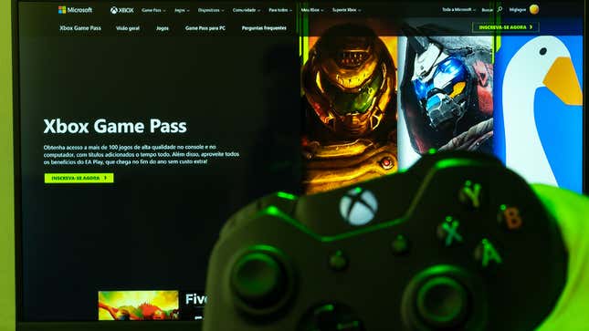 An Xbox controller is held up in front of a screen that shows an Xbox Game Pass menu.