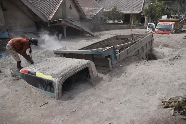 A man inspects a truck buried in the ash following the eruption of Mount Semeru.