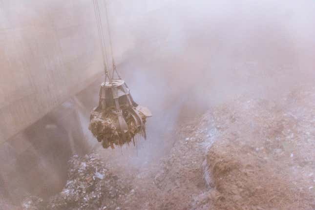 A mechanical claw grabs garbage to feed into the furnace.