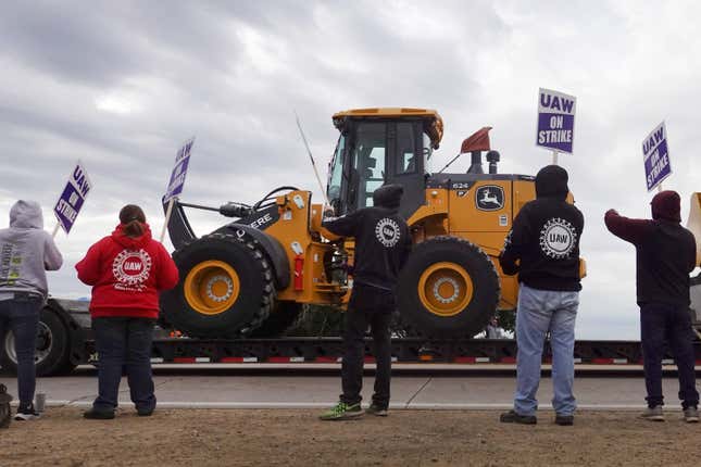 UAW workers protest in front of a John Deere tractor