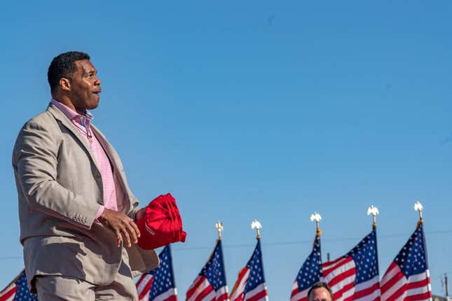  Heisman Trophy winner and Republican candidate for US Senate Herschel Walker throws hats to supporters of former U.S. President Donald Trump during a rally at the Banks County Dragway on March 26, 2022, in Commerce, Georgia. 