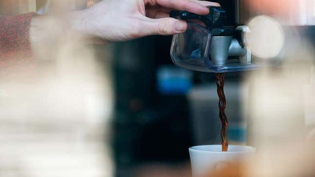 Barista's hand dispensing coffee from drip machine