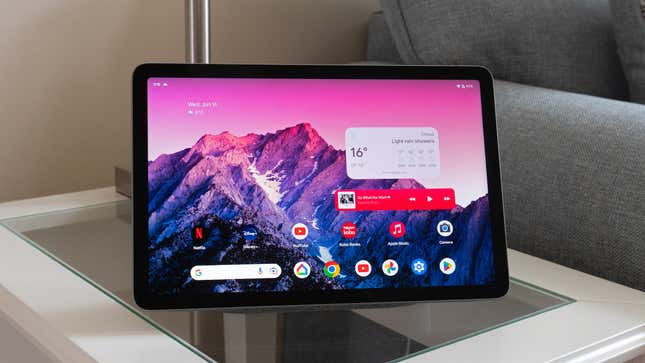 The Android 13 home screen on the Google Pixel Tablet, sitting on a small side table.