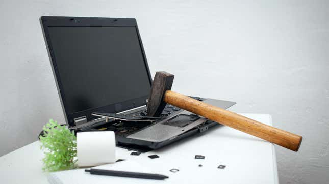 A laptop being broken with a hammer.