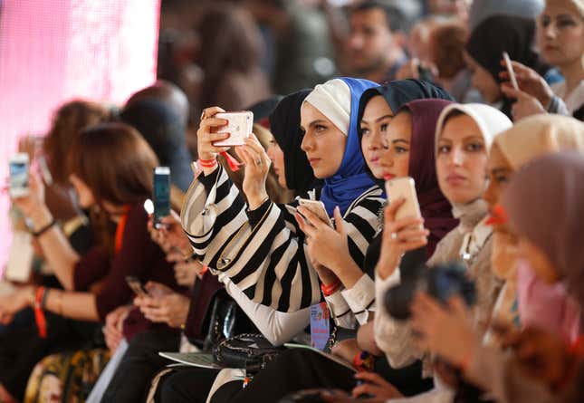 Fashion enthusiasts take pictures during the aunch fashion show of the International Modest Fashion Week, in Istanbul, Friday, May 13, 2016. Turkeys first International Modest Fashion Week has opened in Istanbul bringing designers and models of conservative wear from around the world. The two-day event kicked off Friday with models hitting the runway at a historic train station donning a bright palette of breezy garment and kaleidoscopic headscarves. (AP Photo/Lefteris Pitarakis)