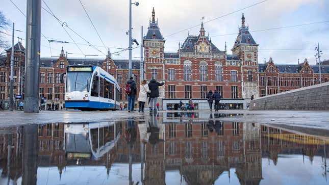A photo of a tram passing the train station in Amsterdam.
