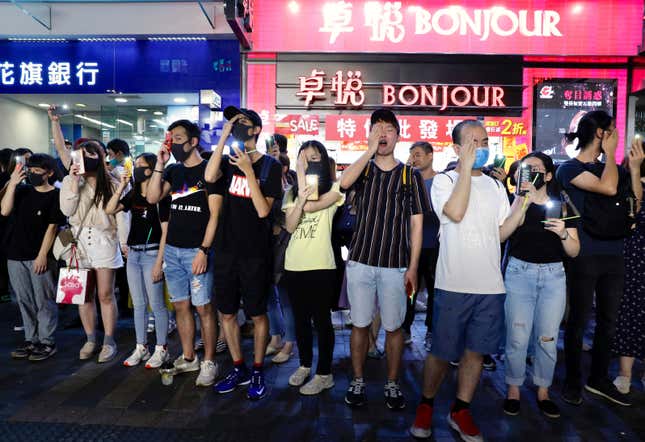 Demonstrators hold their hands to their eyes in solidarity with a woman who suffered a serious eye injury at a previous protest.
