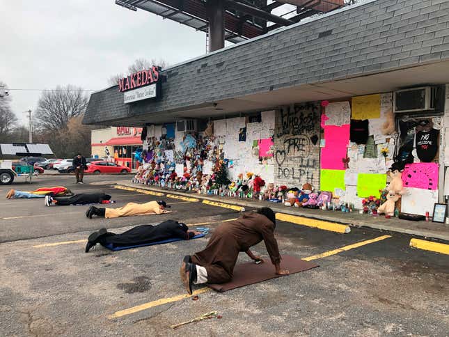 Mourners lie on the ground and pray in front of a memorial to slain rapper Young Dolph at Makeda’s Homemade Cookies in Memphis, Tenn.