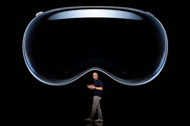 Apple CEO Tim Cook speaks under an image of Apple Vision Pro on stage. 