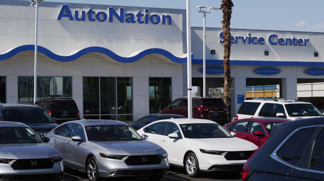 Three Honda Civics lined up in front of a white and blue car dealership. A large blue sign reads AutoNation on the white building. to the right, another sign says Service Center. 