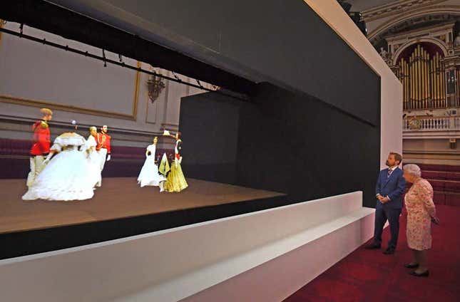 La reina Isabel II observa una técnica de ilusión victoriana conocida como Pepper’s Ghost de un vals bailado en el baile de Crimea de 1856, en el salón de baile del Palacio de Buckingham, como parte de la exposición para conmemorar el 200 aniversario del nacimiento de la reina Victoria para el verano. Inauguración del Palacio de Buckingham en Londres el 17 de julio de 2019