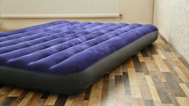 Purple air mattress inflated, lying on wood floor