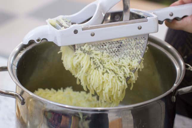 potatoes going through a rice into a pot