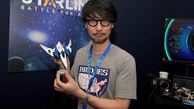 Hideo Kojima holds a spaceship figure at a gaming convention.