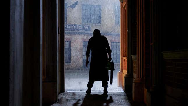 Holding his trademark chainsaw, Leatherface stands silhouetted in a doorway in a scene from 2022's Texas Chainsaw Massacre.