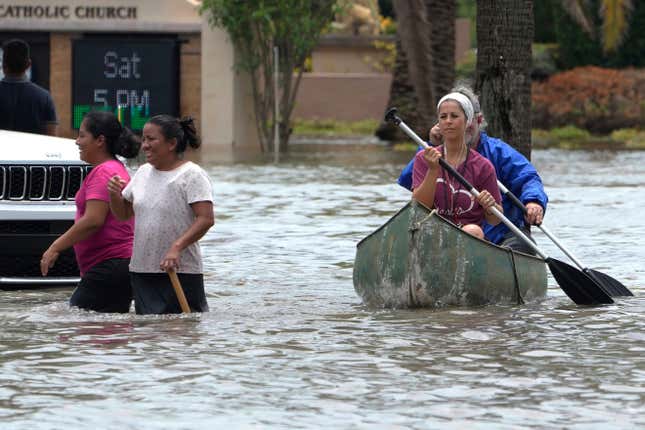 Residents paddle and walk along a flooded road Thursday, April 13, 2023, in Fort Lauderdale, Florida. 