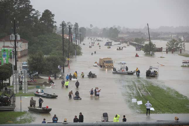 People walk down a flooded street as they evacuate their homes after the area was flooded during Hurricane Harvey on August 28, 2017 in Houston, Texas. 
