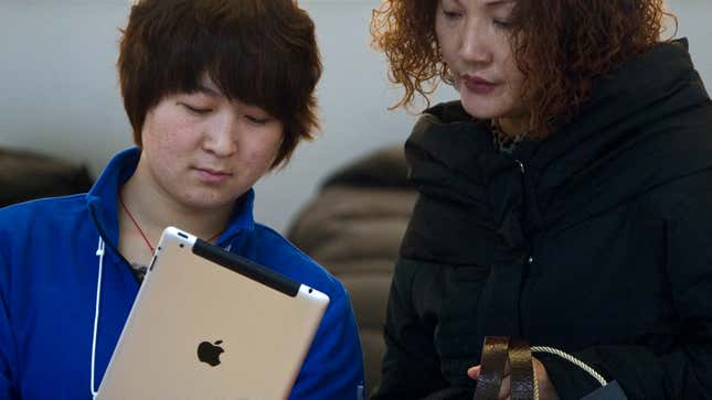 An Apple Store employee shows an iPad2 to a customer in Beijing, China