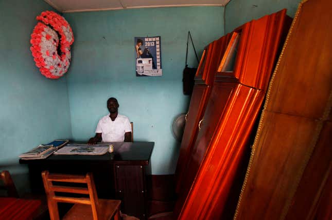 Choosing the right coffins can also prove a pricey affair. Here, a coffin salesman sits at his desk at his business in the Ivory Coast.