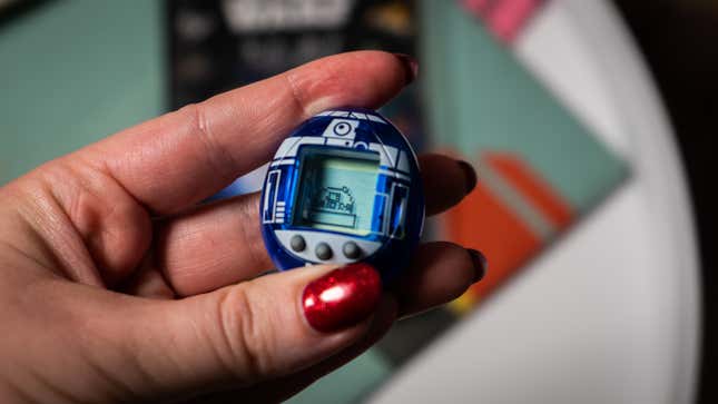 A photo of a person holding the R2-D2 Tamagotchi