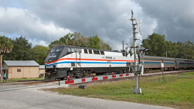 A photo of an Amtrak train at a railroad crossing. 