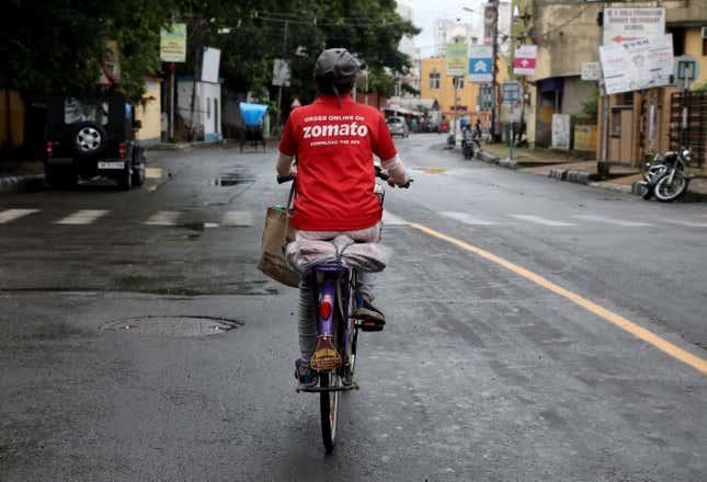 A delivery worker of Zomato rides her bicycle along a road in Kolkata