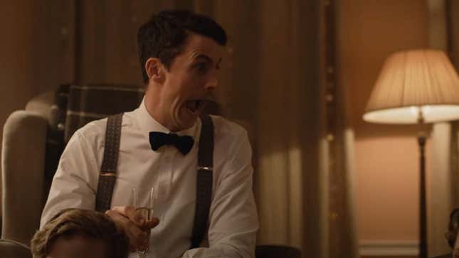 Matthew Goode makes a silly face while a bowtie with no jacket, and holding a glass of champagne.