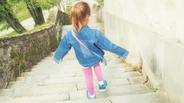 Little girl walking down a staircase.