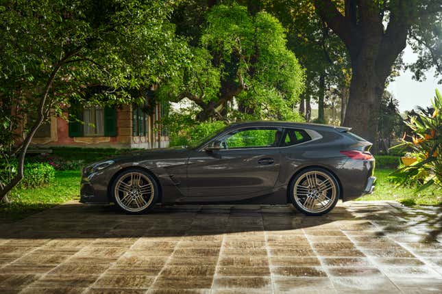 A concept car with BMW brakes is parked in front of a house and trees.  Side.