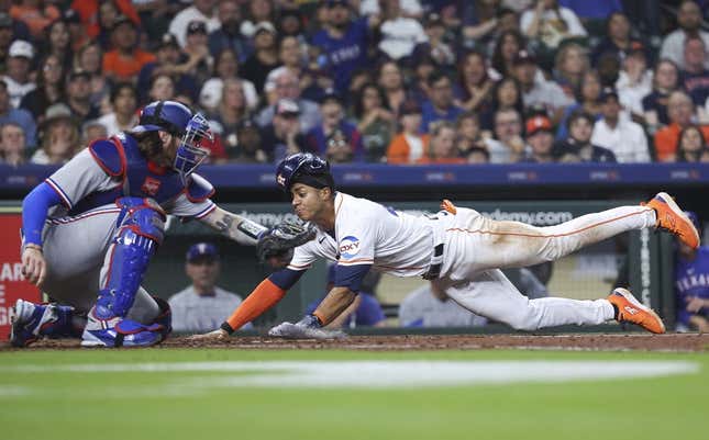 Apr 15, 2023; Houston, Texas, USA; Houston Astros shortstop Jeremy Pena slides safely to score a run as Texas Rangers catcher Jonah Heim attempts to apply a tag during the fourth inning at Minute Maid Park.