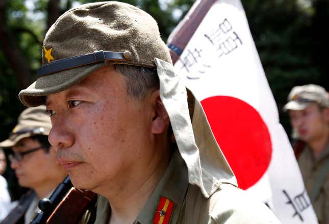 Men dressed as Japanese imperial army soldiers march in front of the gate of the Yasukuni Shrine in Tokyo August 15, 2014, to mark the 69th anniversary of Japan's surrender in World War Two.