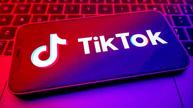 A photo of a smartphone laying on a keyboard shows the TikTok logo on the front. 