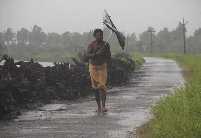 A man struggles with an umbrella in strong winds and rain caused by Cyclone Hudhud in Gopalpur in Ganjam district in Odisha.