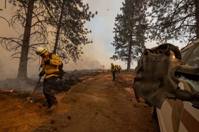 A melted sideview mirror on a firefighting truck is seen as firefighters set a backfire at the Oak Fire on near Mariposa, California, on July 24, 2022.