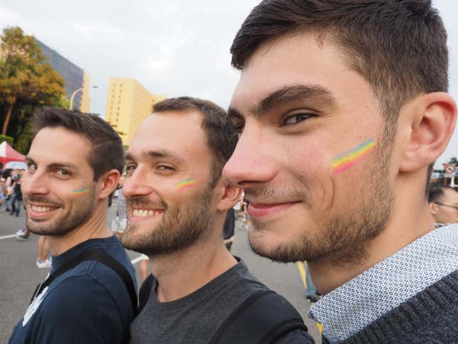Three men show off the rainbow flags on their face during the 2017 Taipei Gay Pride March on 28 Oct. 2017.