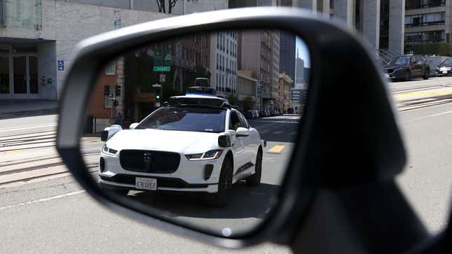 A photo of a self driving car reflected in a rear view mirror. 