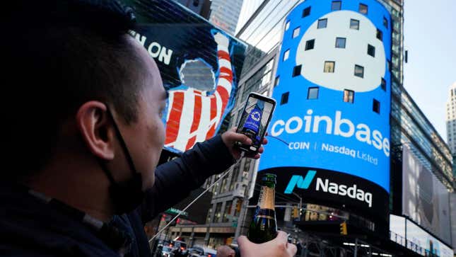 Coinbase employee Daniel Huynh holds a celebratory bottle of champagne as he photographs outside the Nasdaq MarketSite, in New York's Times Square, Wednesday, April 14, 2021.